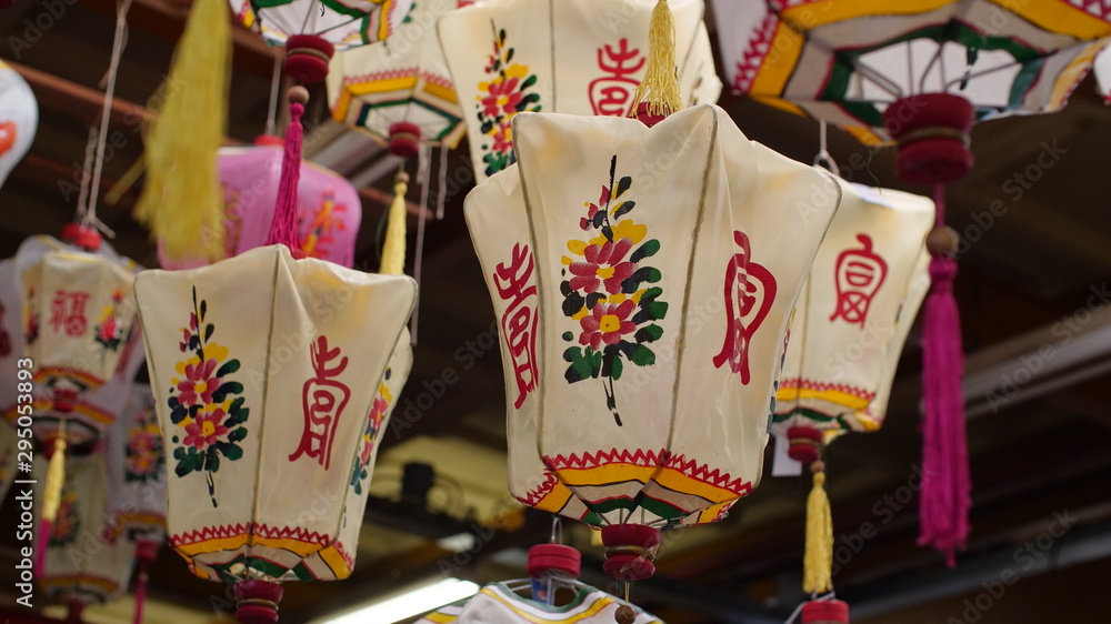 Fototapeta premium A group of old traditional Chinese lanterns hangs in a dusty antique warehouse, they're full of the beautiful script, colour & patterns.