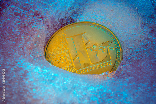 Golden Litecoin coin, lite coin online digital currency frozen in the blue ice. Concept of block chain, market crash. Frozen crypto money, depreciation photo