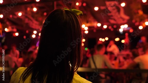 young woman preparing to start wild weekend evening, blurry crowded red district view in background