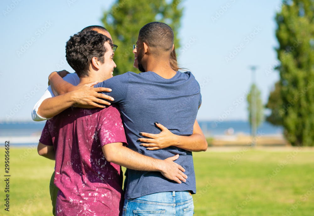 Happy old friends hugging outside. Young men and woman standing in circle on grass and embracing each other. Close friendship or bonding concept Happy old friends hugging outside. Young men and woman standing in circle on grass and embracing each other. Close friendship or bonding concept
