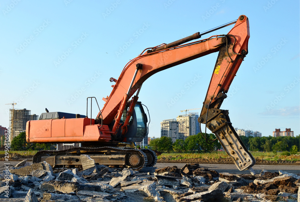 Crawler excavator with hydraulic hammer for the destruction of concrete and hard rock at the construction site. Replacing a concrete runway or road surface at an airport. Roadworks background - Image Crawler excavator with hydraulic hammer for the destruction of concrete and hard rock at the construction site. Replacing a concrete runway or road surface at an airport. Roadworks background - Image