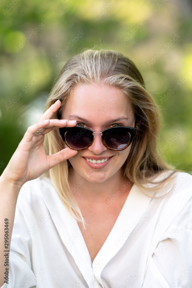 Attractive young woman holding her sunglasses and looking at the camera
