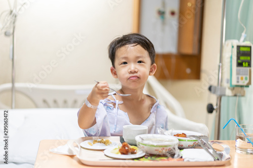 A patient boy is eatting food while he sick in the hospital.