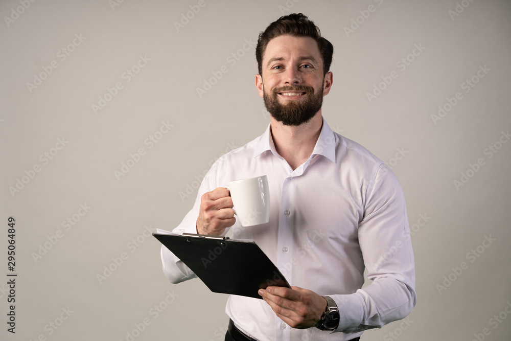 Handsome cheerful and smiling american in a modern office with a cup . Hilding some stats about profits. Handsome cheerful and smiling american in a modern office with a cup . Hilding some stats about profits.