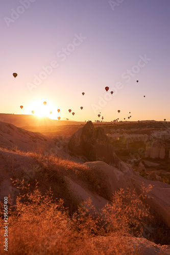 sunrise photo in Cappadocia with air balloons in the sky over sandy hills