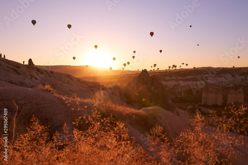 sunrise photo in Cappadocia with air balloons in the sky over sandy hills