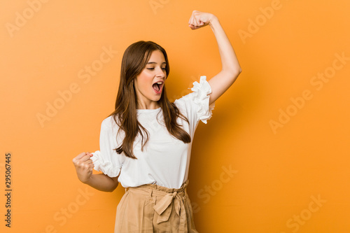 Young caucasian woman raising fist after a victory, winner concept. photo