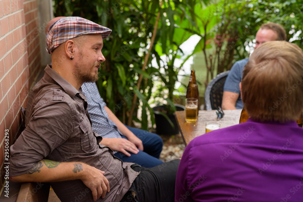 Fototapeta premium Hispter man sitting outdoors with friends while drinking beer