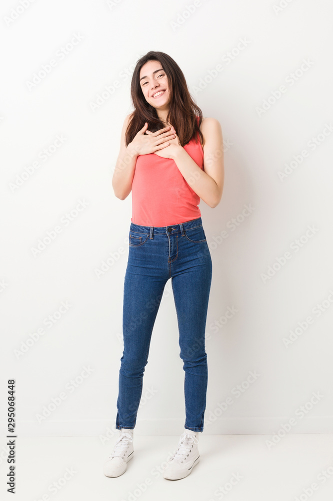 Full body young woman on white background laughing keeping hands on heart, concept of happiness. Full body young woman on white background laughing keeping hands on heart, concept of happiness.
