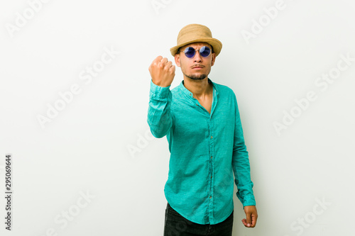 Young hispanic man wearing a summer clothes showing fist to camera, aggressive facial expression.