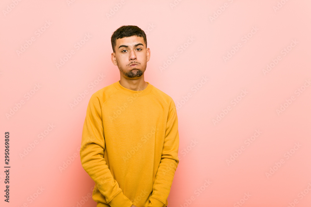 Young hispanic man blows cheeks, has tired expression. Facial expression concept. Young hispanic man blows cheeks, has tired expression. Facial expression concept.