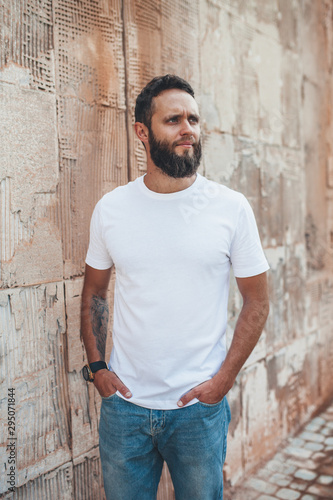 Young hipster man with beard wearing white blank t-shirt and blue jeans outdoor.