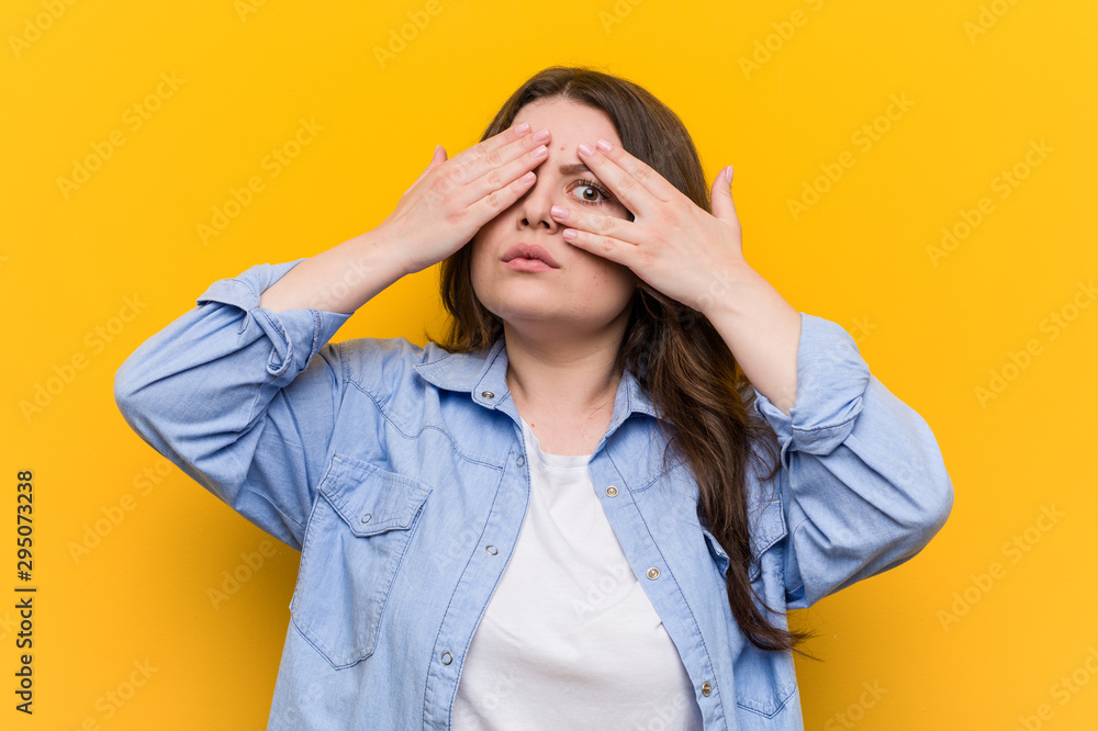 Young curvy plus size woman blink through fingers frightened and nervous. Young curvy plus size woman blink through fingers frightened and nervous.