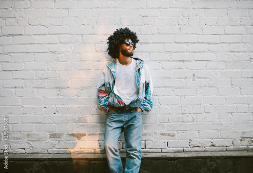 Stylish young man in a retro jacket. Fashion trends of 90s. Handsome hipster guy with beard with curly hair. photo