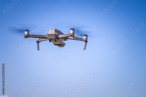 Drone is flying with digital camera to take photo and video on ground with blue sky background.