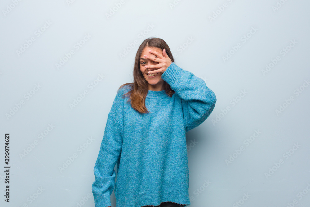 Young pretty woman wearing a blue sweater embarrassed and laughing at the same time Young pretty woman wearing a blue sweater embarrassed and laughing at the same time