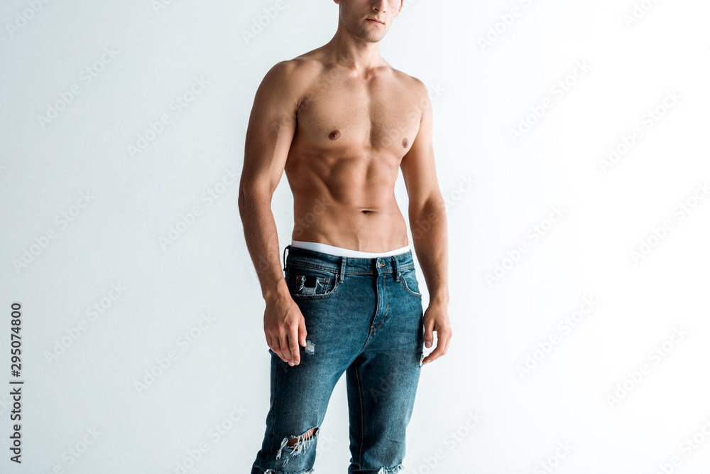 cropped view of shirtless man in jeans standing on white