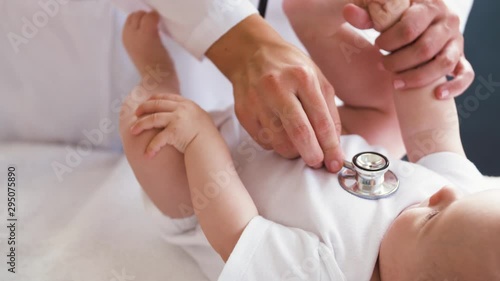medicine, healthcare and pediatrics concept - female doctor with stethoscope listening to baby girl's patient heartbeat or breath at clinic or hospital