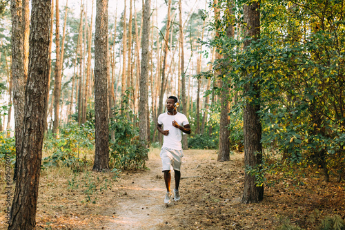 Sporty African American listening to music with headphones Jogging in the woods © Shopping King Louie