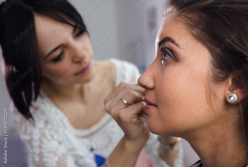 Young female make-up artist applying makeup on model in beauty salon. Young female make-up artist applying makeup on model in beauty salon.
