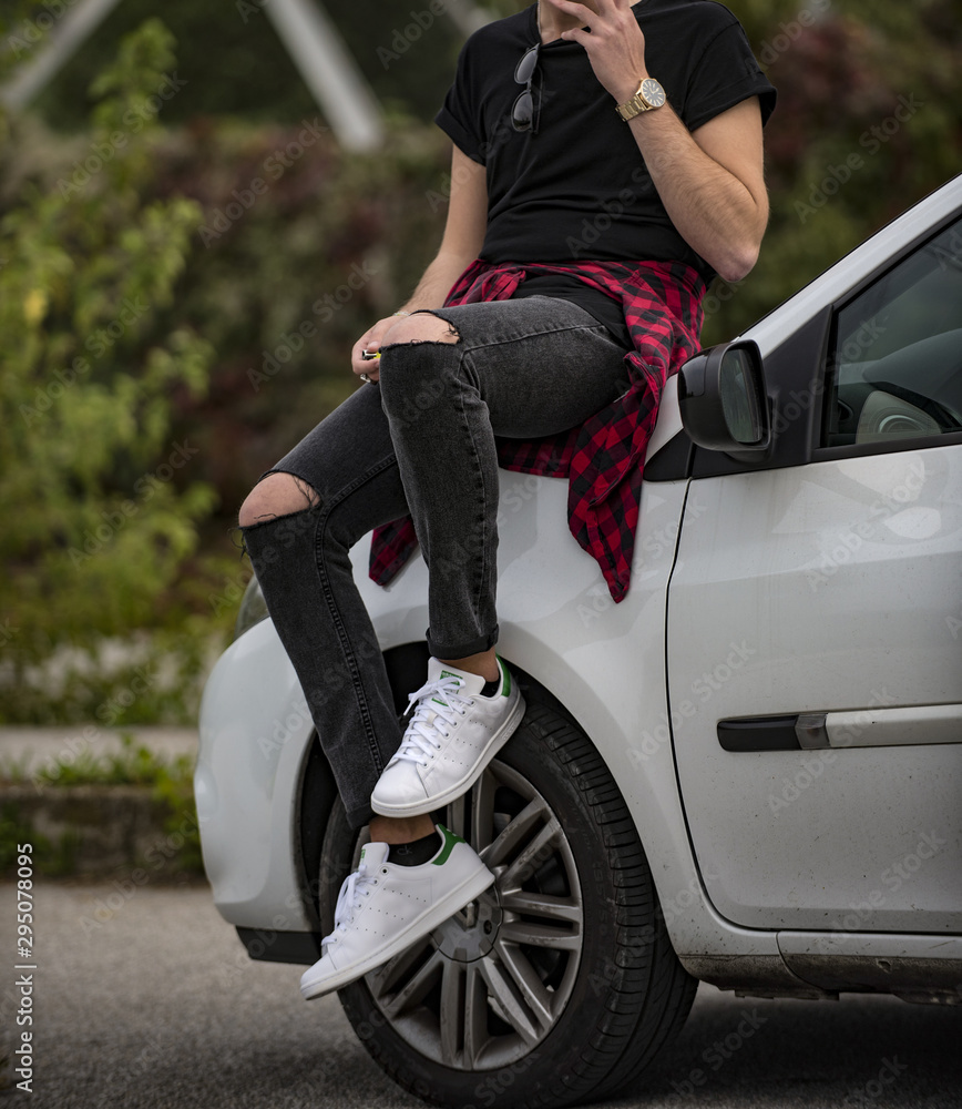 Young man wearing Adidas Stan Smith shoes and sitting on a white car Photos  | Adobe Stock