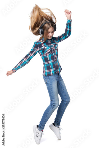 Teen girl in checkered shirt dancing listening music in headphones
