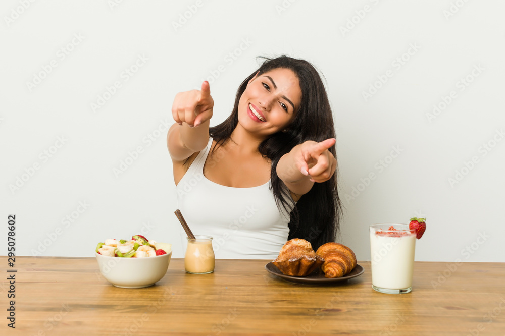 Young curvy woman taking a breakfast cheerful smiles pointing to front. Young curvy woman taking a breakfast cheerful smiles pointing to front.