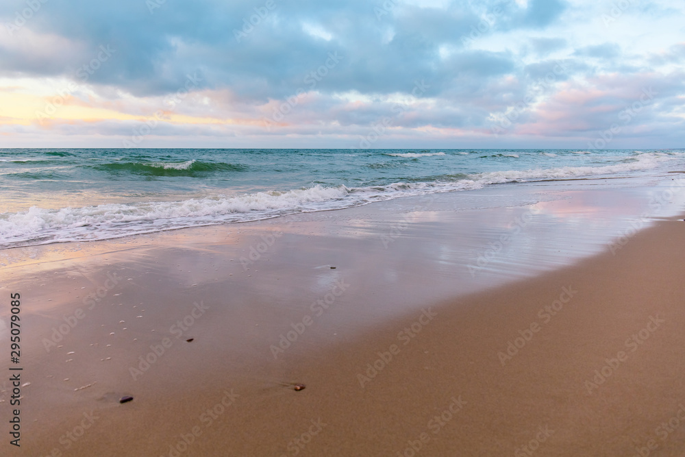 sandy beach by the turquoise sea in cloudy weather in sunset light sandy beach by the turquoise sea in cloudy weather in sunset light