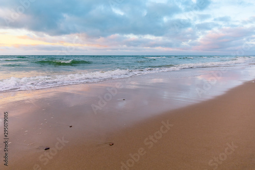 sandy beach by the turquoise sea in cloudy weather in sunset light