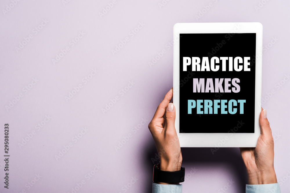 cropped view of woman holding digital tablet with practice makes perfect lettering on purple cropped view of woman holding digital tablet with practice makes perfect lettering on purple