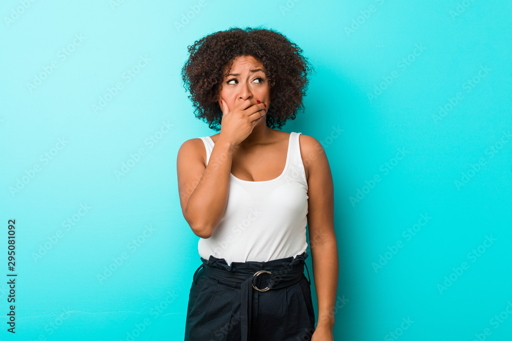 Young african american woman thoughtful looking to a copy space covering mouth with hand. Young african american woman thoughtful looking to a copy space covering mouth with hand.