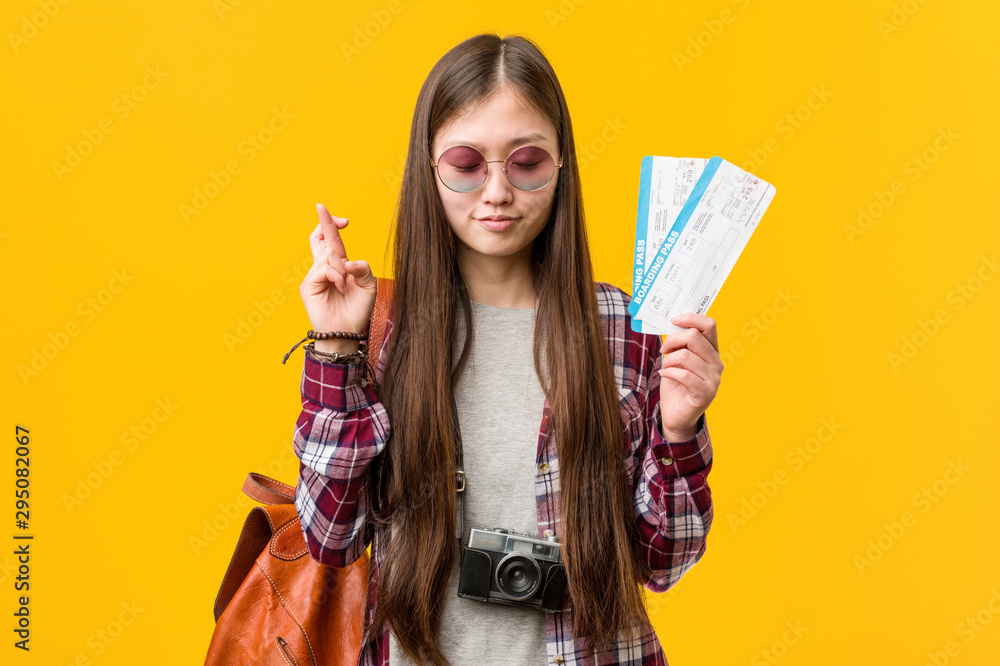 Young asian woman holding an air tickets crossing fingers for having luck Young asian woman holding an air tickets crossing fingers for having luck