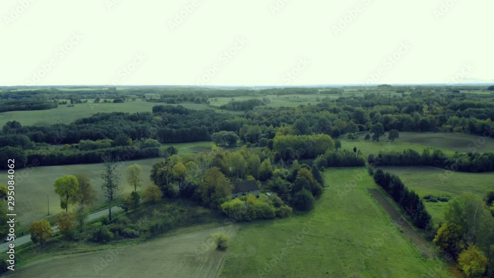 Slow aerial dolly forward shot, showing road with car and amazing green nature landscape with forest and green farming fields Slow aerial dolly forward shot, showing road with car and amazing green nature landscape with forest and green farming fields