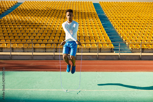Canvas Print Young handsome African American sportsman jumping on skipping rope during workou