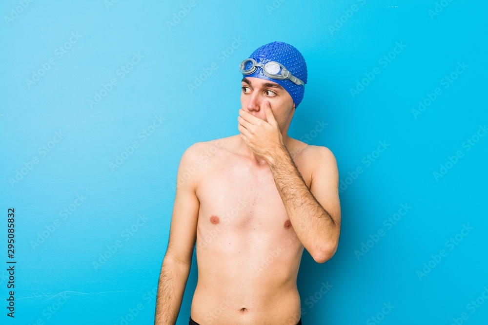 Young swimmer man thoughtful looking to a copy space covering mouth with hand. Young swimmer man thoughtful looking to a copy space covering mouth with hand.