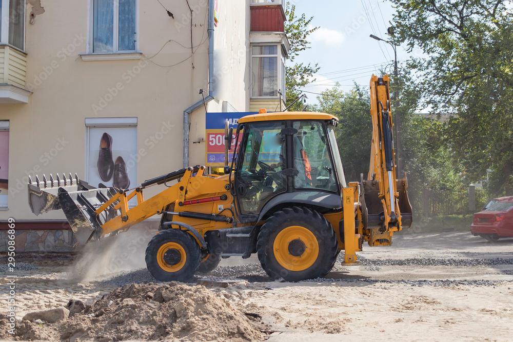 Orange excavator on wheels works in the city Orange excavator on wheels works in the city