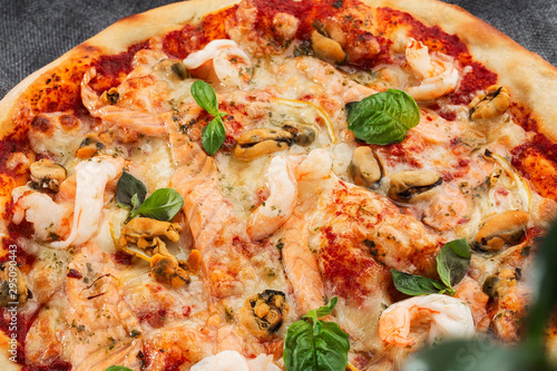 Seafood Italian pizza with shrimp squid  mussels  fresh herbs and mozzarella on a crusty base viewed from above on Gray background. Horizontal photo.