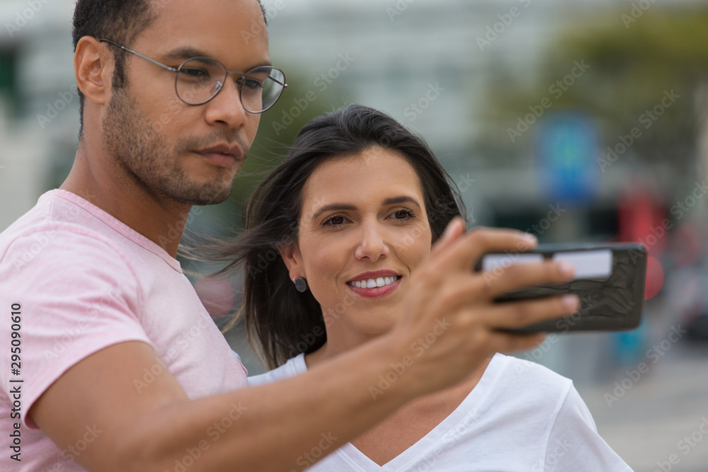Happy multiracial couple taking self portrait with phone. handsome African American man holding smartphone in outstretched arm. Concept of self portrait Happy multiracial couple taking self portrait with phone. handsome African American man holding smartphone in outstretched arm. Concept of self portrait