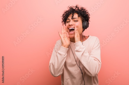 Young african american woman listening to music shouting excited to front.