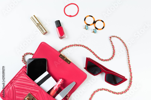 Fashion concept : Flat lay of purple leather woman bag open out with sunglasses and smartphone on white background. - Image