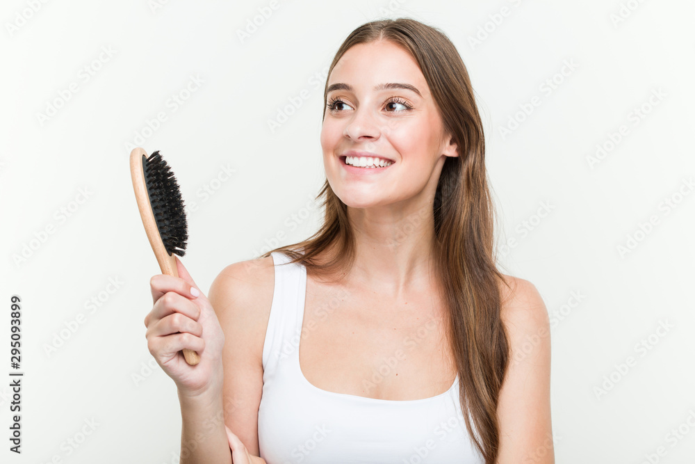 Young caucasian woman holding a hair brush smiling confident with crossed arms. Young caucasian woman holding a hair brush smiling confident with crossed arms.