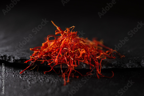 Saffron dry petals spices heap on black slate stone table