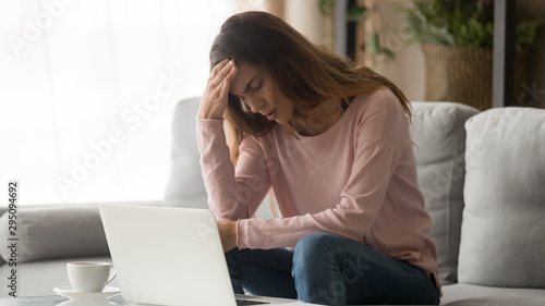 Tired stressed unhappy woman suffering from headache at home