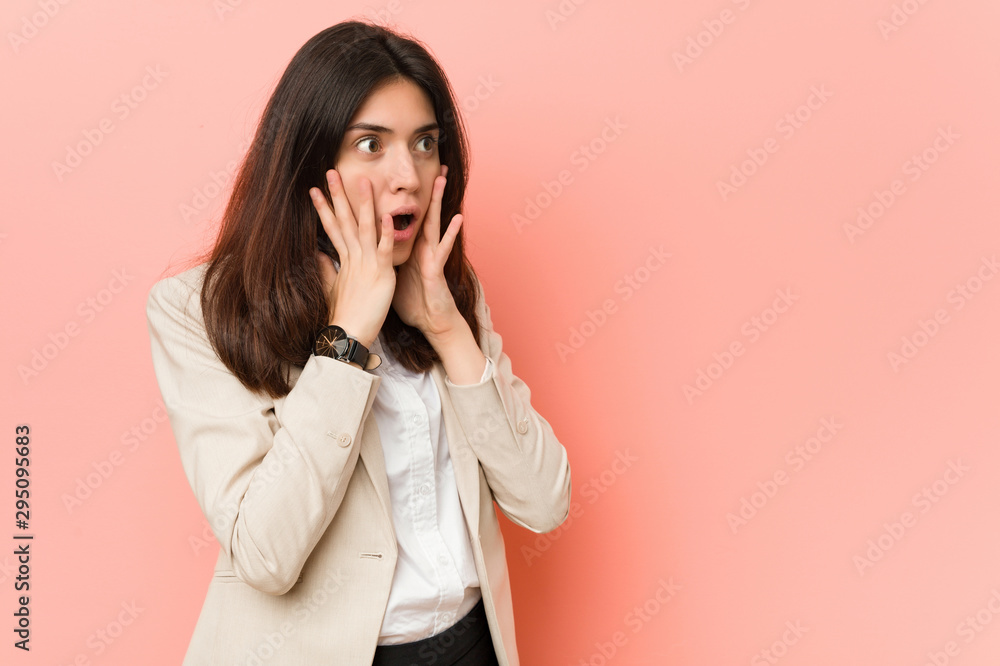 Young brunette business woman against a pink background shouts loud, keeps eyes opened and hands tense. Young brunette business woman against a pink background shouts loud, keeps eyes opened and hands tense.