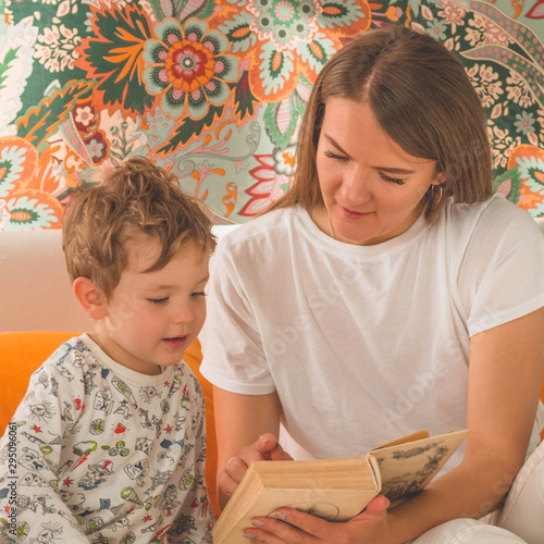 Pretty young mother reading a book to her little son in modern interior photo