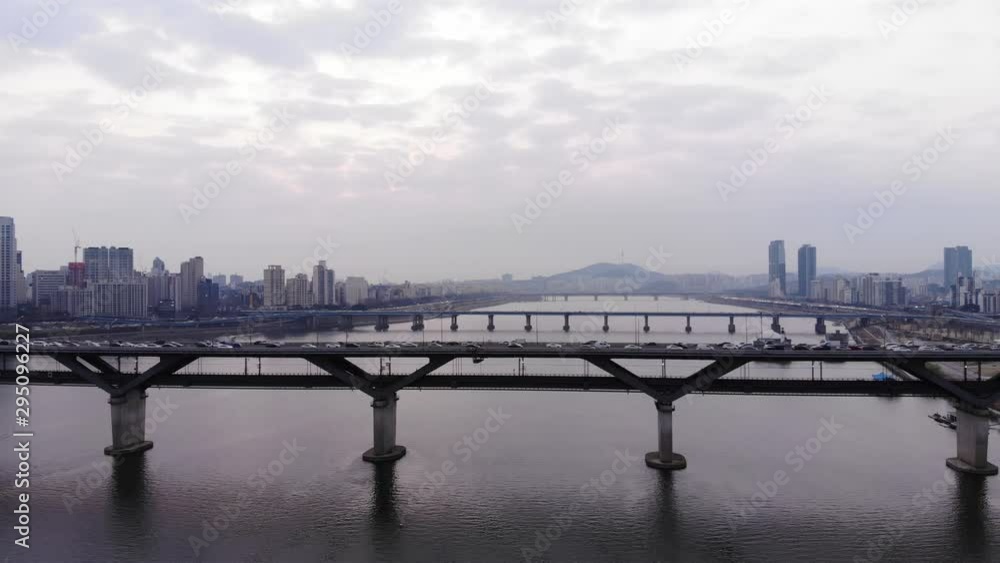 Aerial panorama of Han RIver and Seoul metropolis. Camera fly back, Cheongdam Bridge on foreground. Cloudy sky, light industrial mist in air. Busy traffic on Dongbu Expressway. Aerial panorama of Han RIver and Seoul metropolis. Camera fly back, Cheongdam Bridge on foreground. Cloudy sky, light industrial mist in air. Busy traffic on Dongbu Expressway.