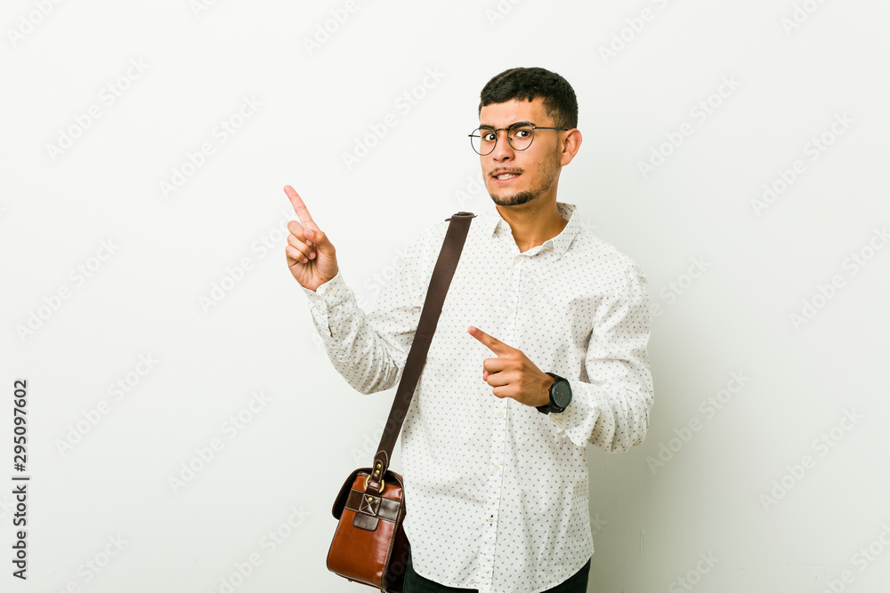 Young hispanic casual business man shocked pointing with index fingers to a copy space. Young hispanic casual business man shocked pointing with index fingers to a copy space.