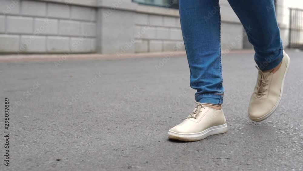 Shot of women feets in sneakers walking on tile road. Urban Environment. Shot of women feets in sneakers walking on tile road. Urban Environment.