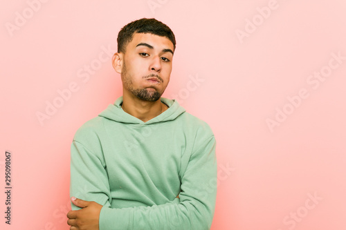 Young hispanic sport man blows cheeks, has tired expression. Facial expression concept.