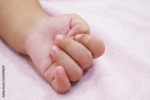 Right hand side of a baby on pink background. Newborn baby hand